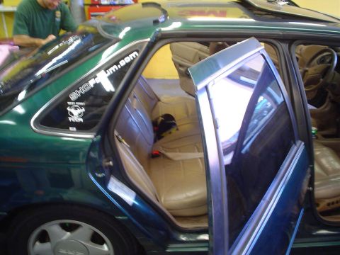 1993 Ford Taurus - Tinting the rear windows of a 1993 Ford Taurus, showing the interior and a worker.