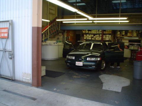 1993 Ford Taurus - A dark green 1993 Ford Taurus is parked inside a garage with its doors open.