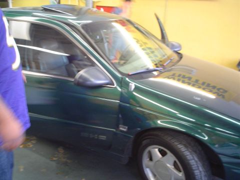 1993 Ford Taurus - A green sedan is parked indoors, with the driver's side door ajar and a sunroof open.
