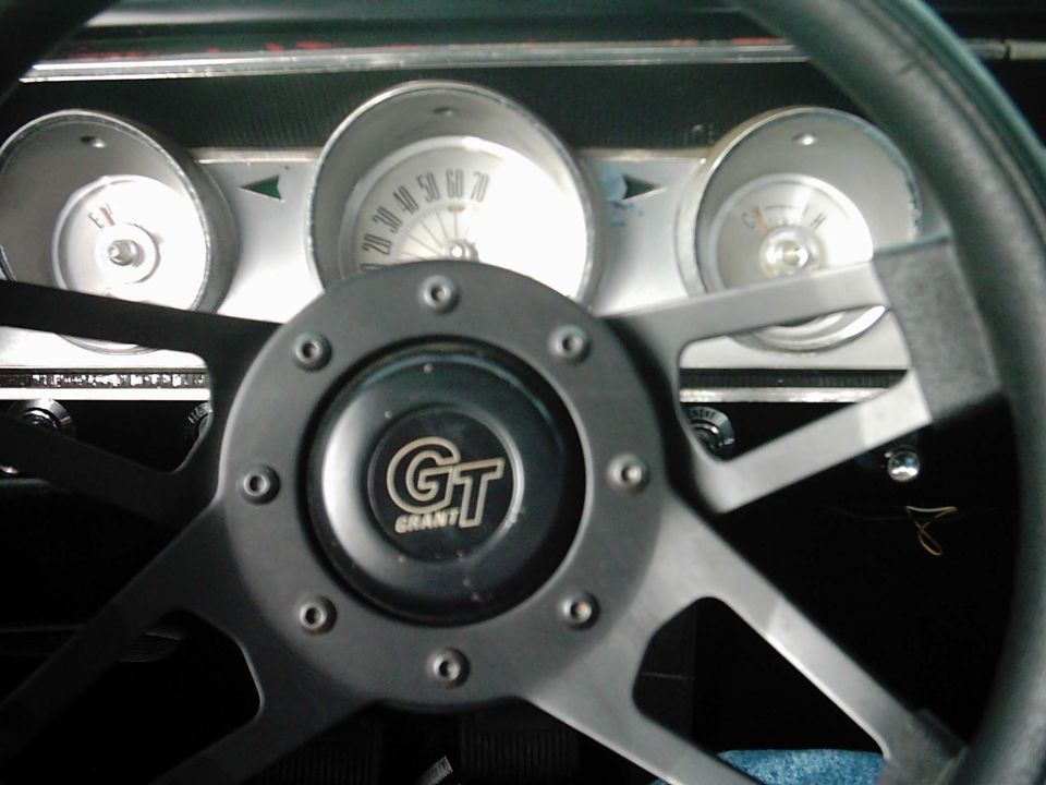 Black Grant GT steering wheel in front of chrome-bezel dash gauges including center speedometer