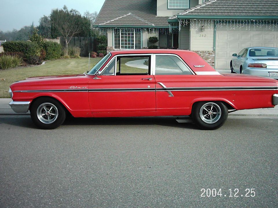 Red 1963 Ford Fairlane two-door hardtop with chrome wheels parked at curb