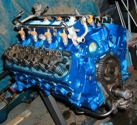1990 Ford Bronco - Engine block painted blue, showing fuel injectors, rocker arms, and timing chain assembly.