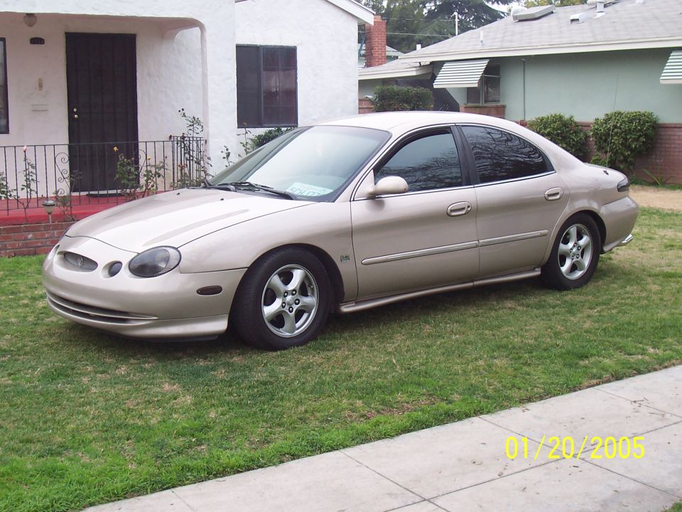 tan sedan parked on grass in front of a house. Date stamp says 01/20/2005
