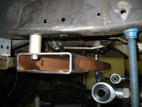 1992 Ford Bronco - Underbody shot of a fabricated steel plate clamped around a rusty frame crossmember, with a white nylon or urethane bumper stop bolted to i…
