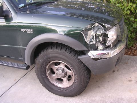 1985 Ford Bronco - Front passenger side of a green Ford Ranger XLT shows significant damage to the fender and headlight assembly.
