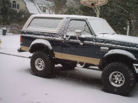 1989 Ford Bronco - A dark blue and tan Ford Bronco sits covered in snow on a winter day.