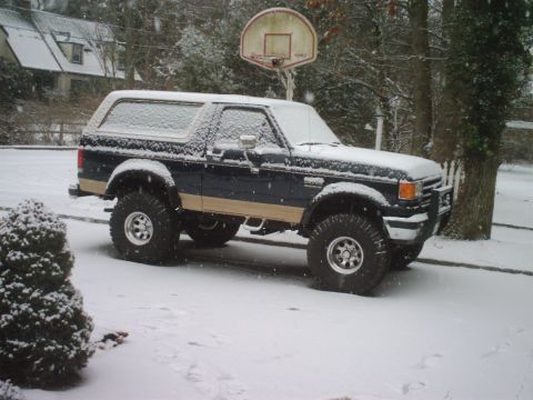 1989 Ford Bronco - Ford Bronco with lifted suspension sits covered in snow during a winter snowfall.
