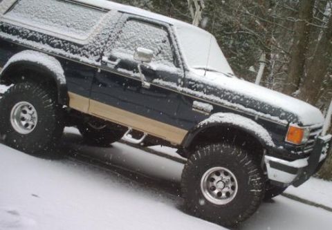 1989 Ford Bronco - A lifted Ford Bronco is parked on a snow-covered hill during winter.