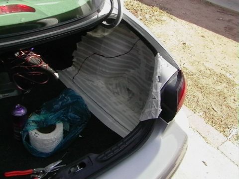 1999 Ford Taurus - The trunk of a silver sedan shows a roll of tape, a spray can, and tools, with the taillight visible.