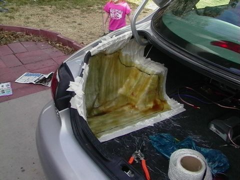 1999 Ford Taurus - The trunk of a silver sedan shows a partially formed fiberglass mold, with tools and tape visible. A young child stands behind the car.