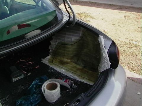1999 Ford Taurus - The trunk of a car is shown with materials for fiberglass work, including matting and tape.