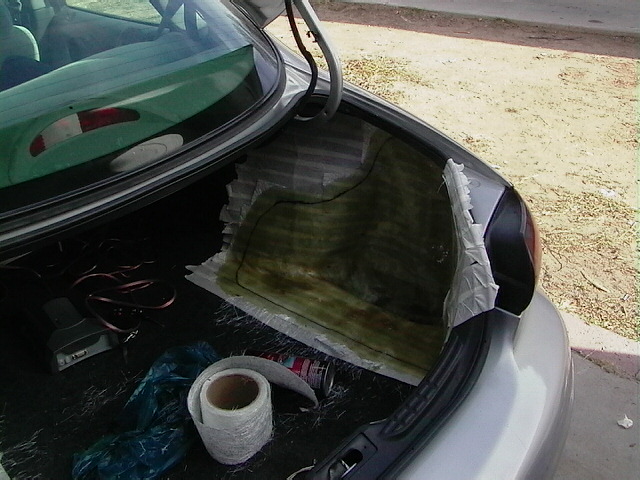 Trunk interior with fiberglass matting and supplies. Rear view