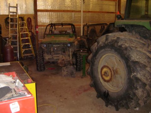1992 Ford Bronco - A green Suzuki Samurai is parked in a garage next to a tractor.