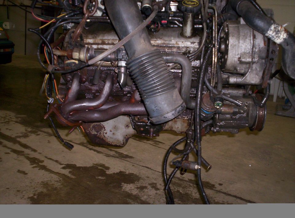 Dirty engine with exhaust manifold, air intake hose, and alternator