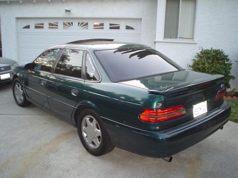 1993 Ford Taurus - This sedan has a spoiler and tinted windows, parked in a driveway.