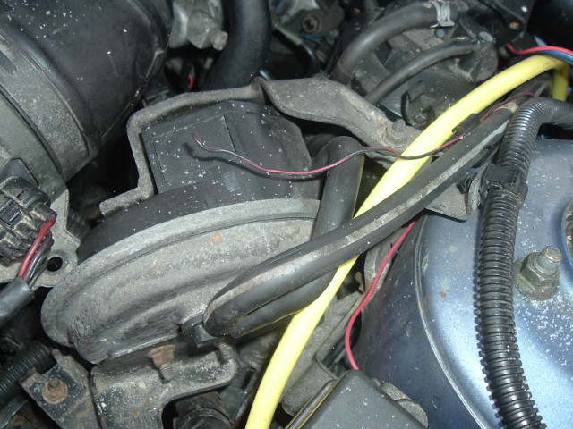 Close-up of engine parts with hoses and wires visible
