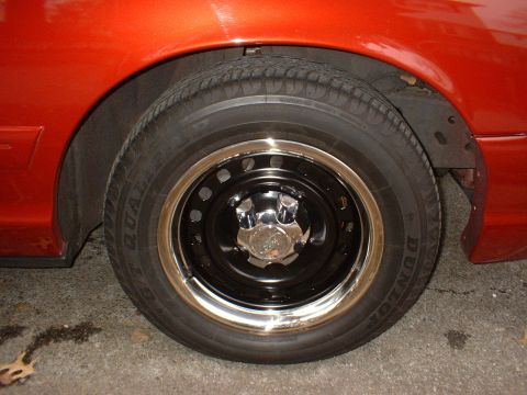 1999 Ford Crown Victoria - Close-up of a wheel and fender on an orange vehicle.