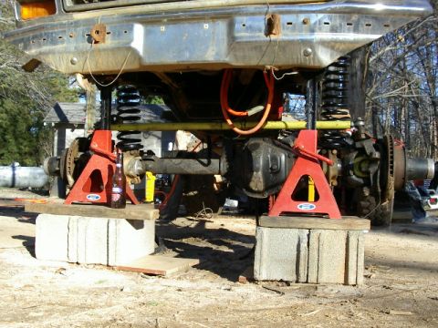1985 Ford Bronco - Front end of a 1985 Ford Bronco undergoing work, supported by jack stands and cinder blocks.