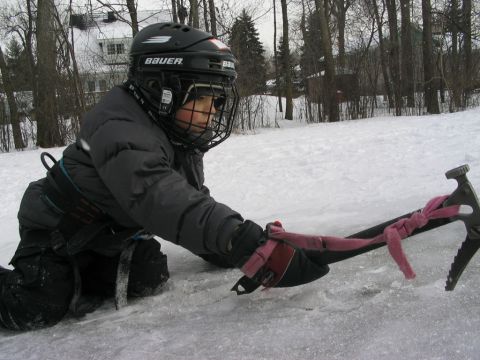 1986 Ford Bronco - A child in hockey gear lies on the ice, holding a pickaxe with a pink scarf tied to it.