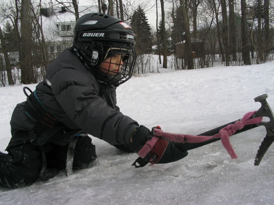 Child in hockey gear on ice with a pickaxe