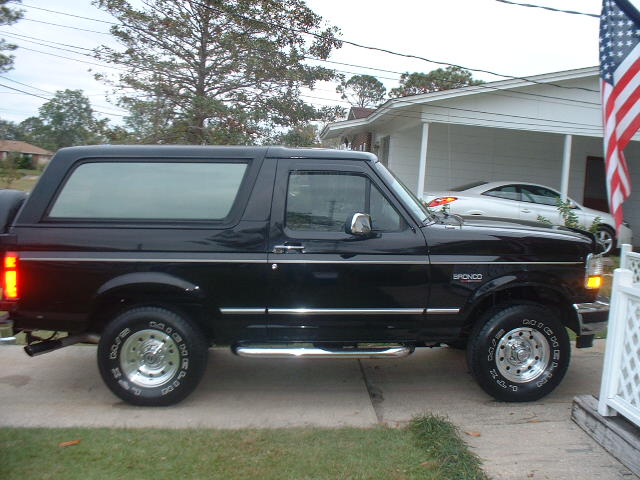 Black two-door Ford Bronco SUV in side profile parked in a driveway