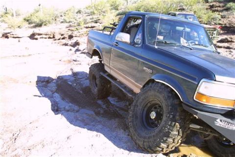 1994 Ford Bronco - A modified Ford Bronco navigates a challenging rocky path, with another vehicle visible in the background.