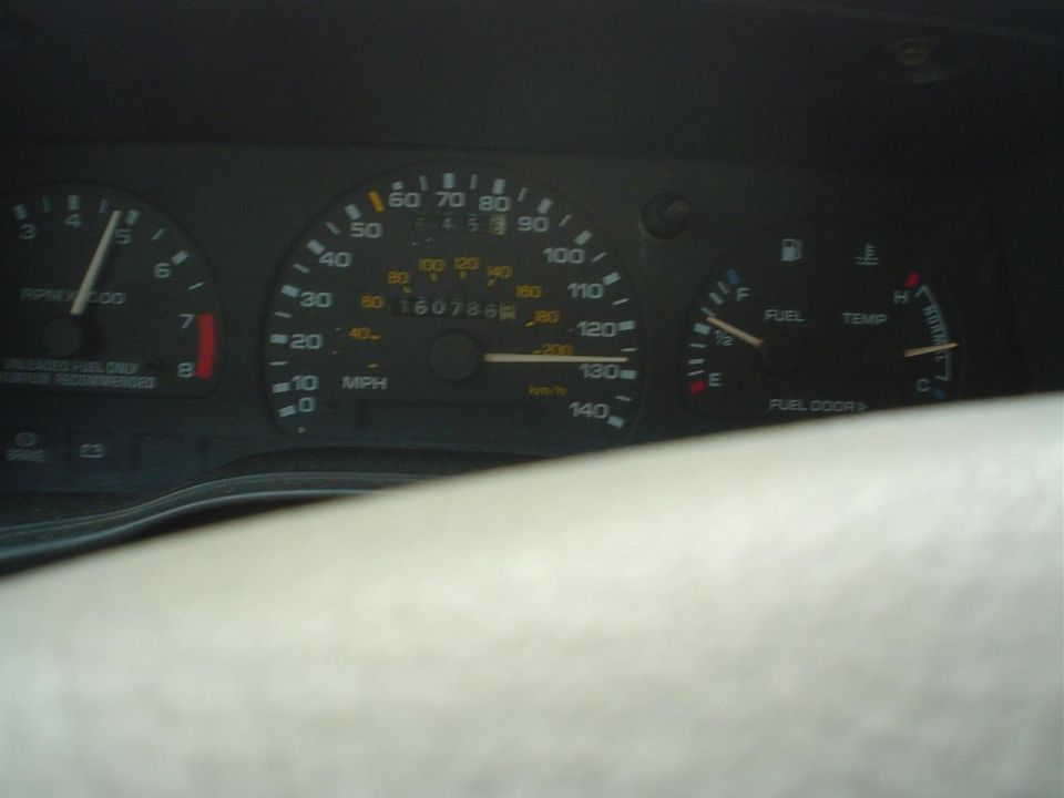 Car dashboard showing speedometer, tachometer, fuel, and temperature gauges. Odometer reads 160786