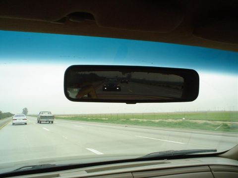 1993 Ford Taurus - The reflection in the rearview mirror shows a 1993 Ford Taurus driving on the highway.