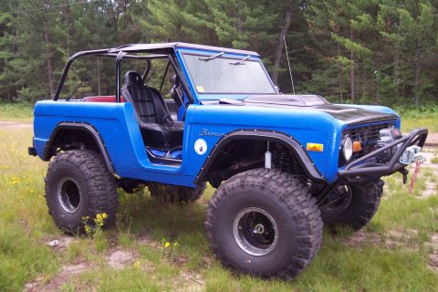 1974 Ford Bronco - Modified 1974 Ford Bronco sits in a grassy field, ready for off-road adventures.