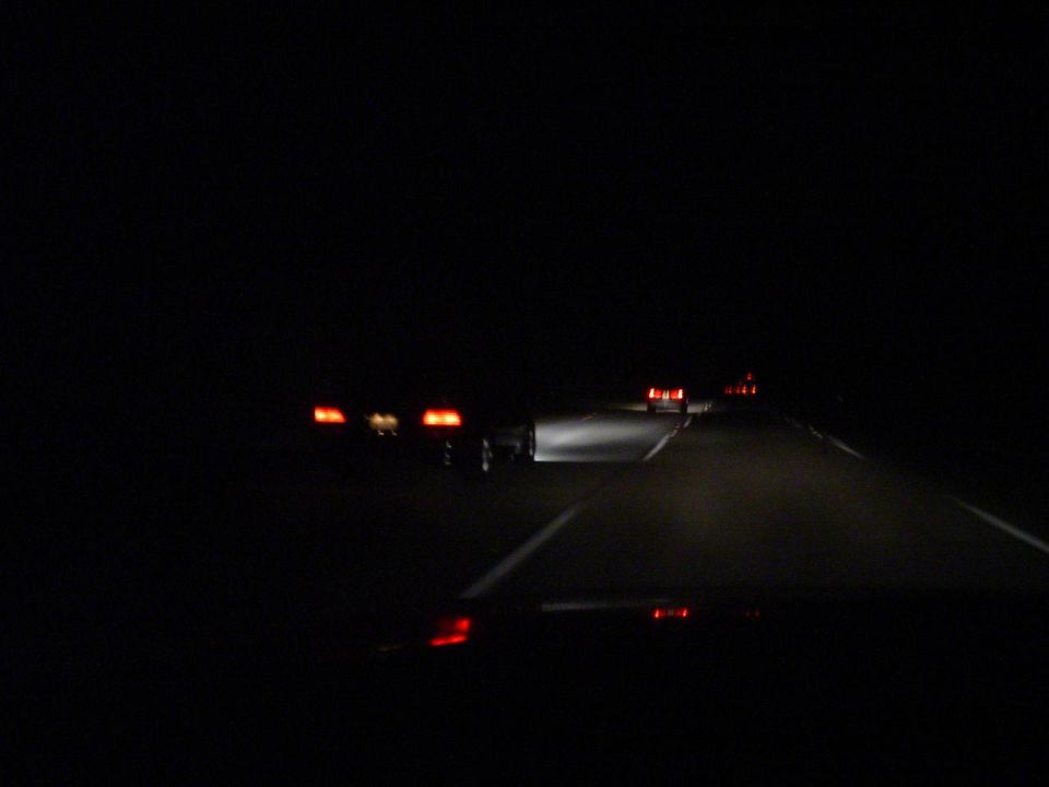 Multiple cars driving on a highway at night, headlights and taillights visible