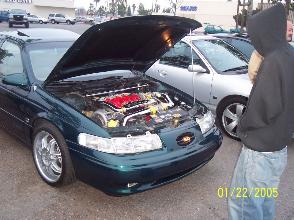 1998 Mercury Sable with hood open showing modified engine, parked next to a silver sedan