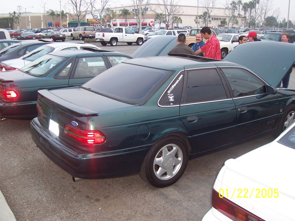 Green sedan with a spoiler and sunroof, parked in a lot