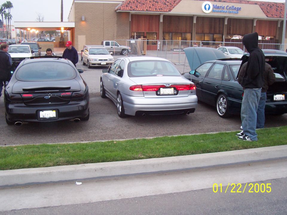 Black Ford Taurus parked next to a silver sedan and a dark green sedan