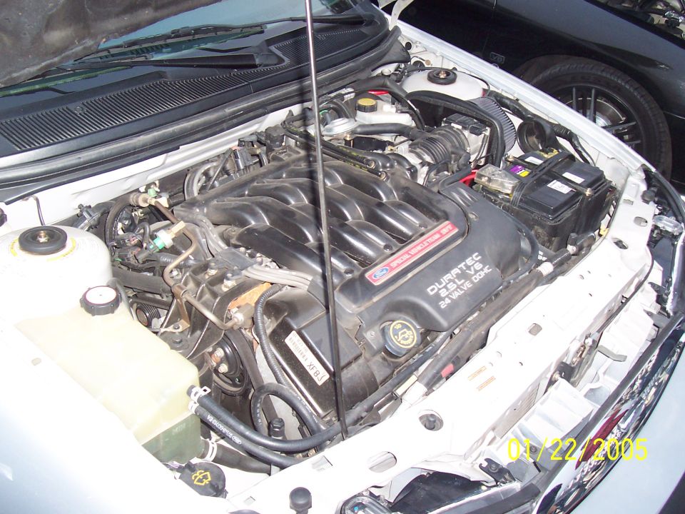 Engine bay with Duratec 2.5L V6 24 Valve DOHC engine cover visible. Another car is parked behind
