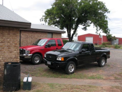 2003 Ford Ranger - A black Ford Ranger pickup truck is parked in front of a red Ford Excursion SUV.