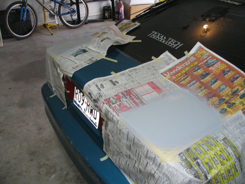 Truck tailgate and bumper masked with newspaper and tape for painting in a garage