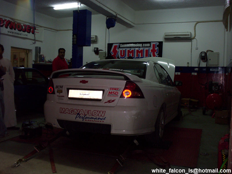 White sedan with a spoiler on a dynamometer, rear view. Magnaflow exhaust sticker visible