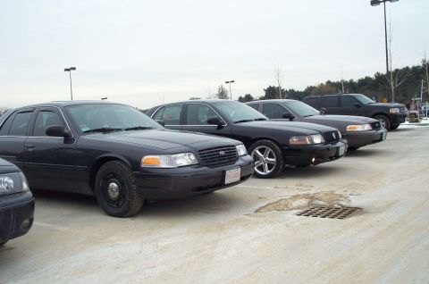 2001 Ford Crown Victoria - Several Ford Crown Victoria police cars are lined up in a parking lot on an overcast day.