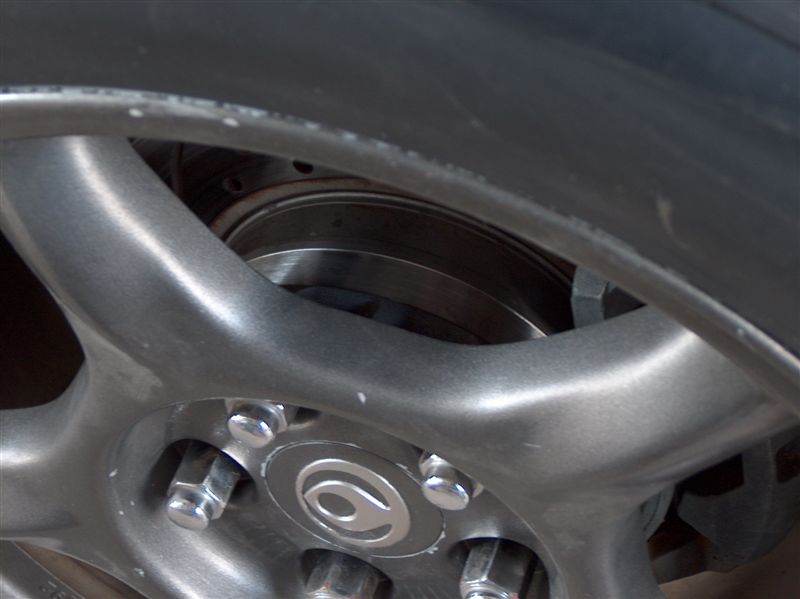 Close-up of a car wheel, brake rotor, and lug nuts