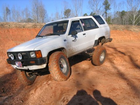1986 Ford F-150 - A white Toyota 4Runner navigates a muddy off-road course, its tires caked in dirt.