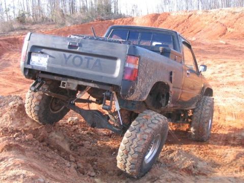 1986 Ford F-150 - This lifted Toyota pickup truck navigates a steep, muddy incline, its off-road capabilities and tires.