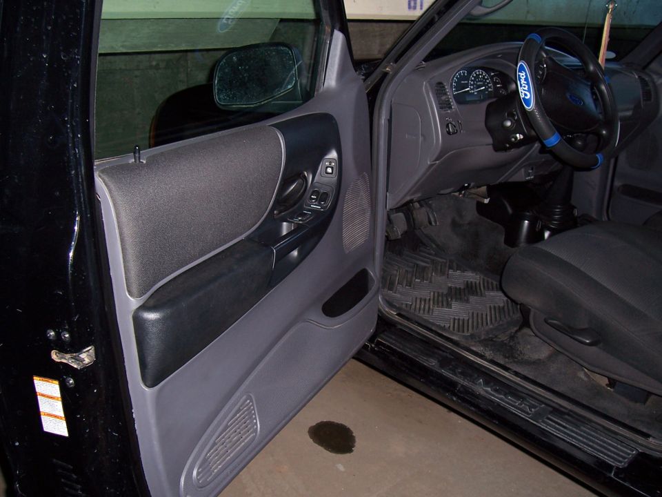2003 Ford Ranger interior showing door panel, dashboard, steering wheel, and floor mats
