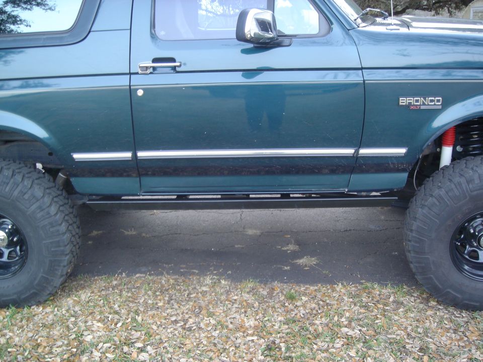 Side profile of lifted green Ford Bronco showing BRONCO XLT door badge
