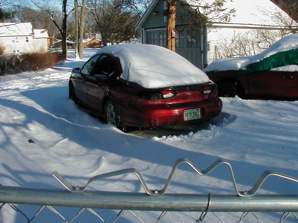 Red 1997 Ford Taurus in snow, rear view. License plate 76 X 1541