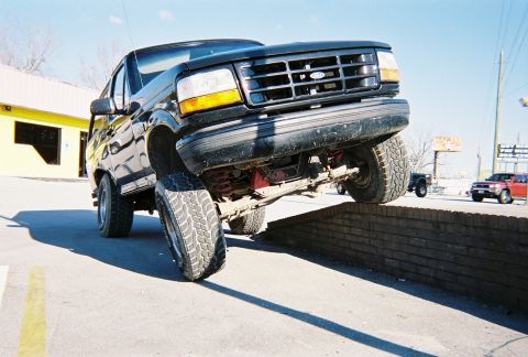 1996 Ford Bronco - A black Ford Bronco is shown with its front passenger tire elevated on a brick wall.