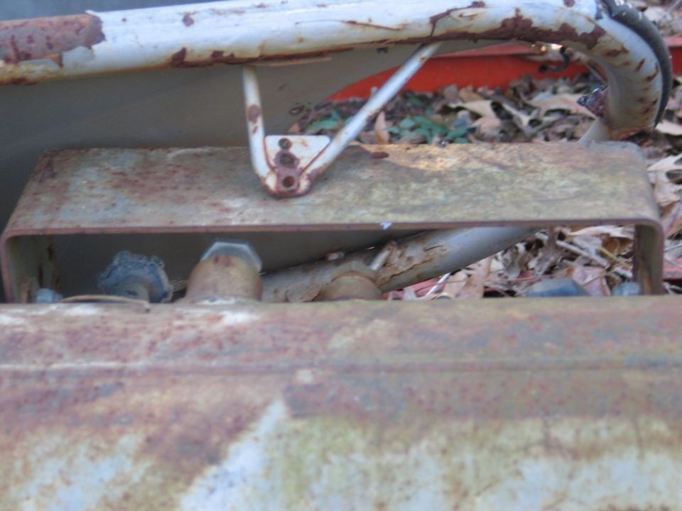 rusted metal frame and pipes, some leaves on the ground