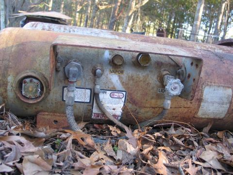 1989 Ford F-150 - This rusty propane tank has visible vapor and liquid valves, and a warning label attached.