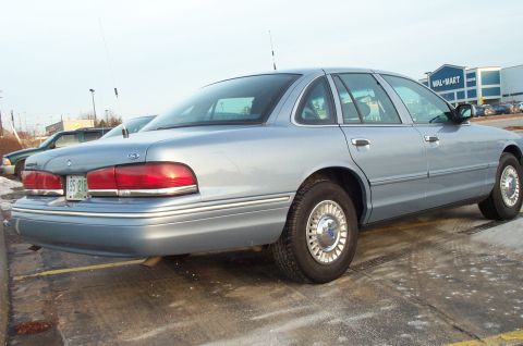 2001 Ford Crown Victoria - A light blue 2001 Ford Crown Victoria sedan is seen from the rear 3/4 angle in a parking lot with a Wal-Mart in the background.