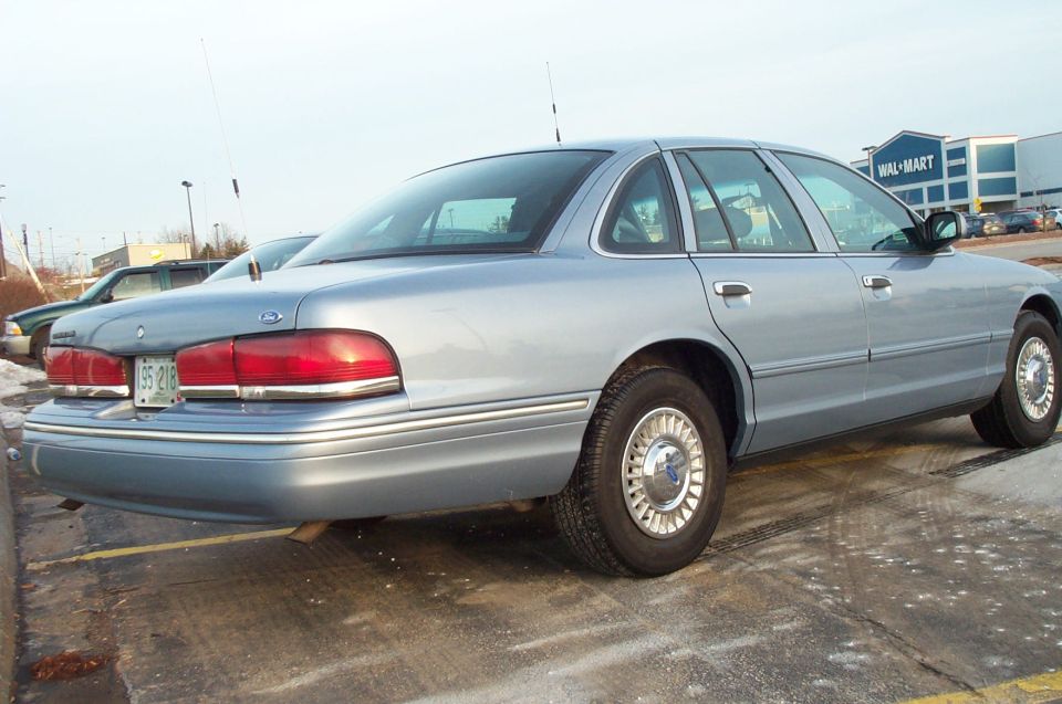 Light blue 2001 Ford Crown Victoria sedan, rear 3/4 view, parked in a lot