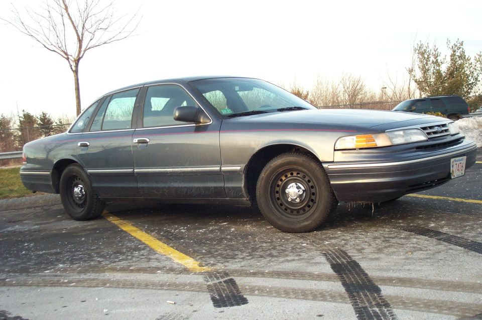 Side view of a 2001 Ford Crown Victoria parked on a wet, icy lot with tire marks